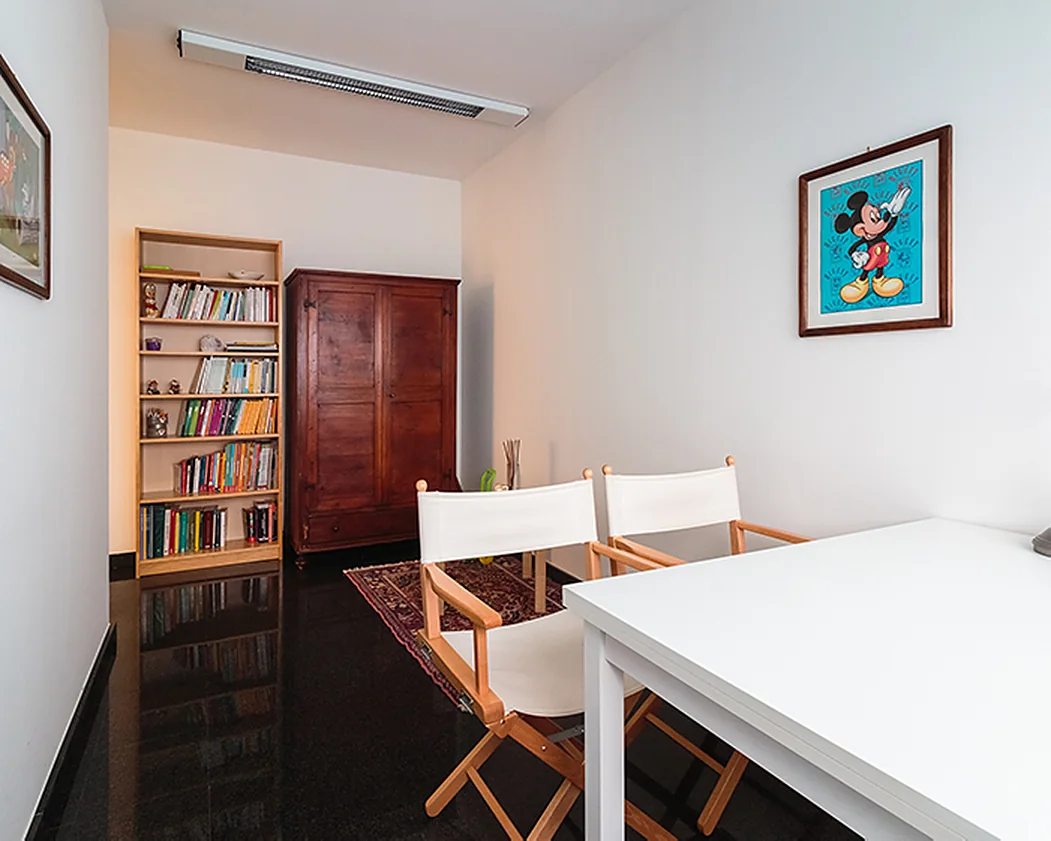 Una stanza con due sedie, un armadio di legno e una libreria